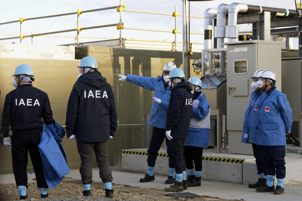 International Atomic Energy Agency Director General Rafael Mariano Grossi, center right, and Tokyo Electric Power Co. (TEPCO) President Tomoaki Kobayakawa, center left, speak at a facility for sampling treated and diluted radioactive water at the Fukushima Daiichi nuclear power plant, operated by TEPCO, in Futaba town, northeastern Japan, Wednesday, March 13, 2024. (AP Photo/Eugene Hoshiko, Pool)