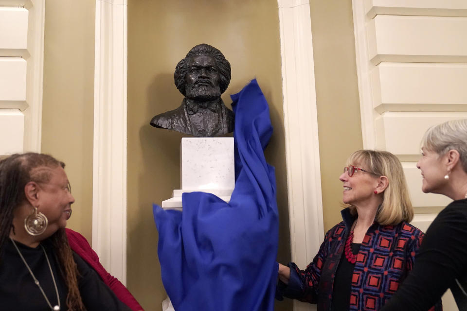 L'Merchie Frazier, member of the State House Art Commission, front left, Karen Spilka, president of the Massachusetts Senate, center right, and Nina Lillie LeDoyt, daughter of artist Lloyd Lillie, right, unveil a bust of famed abolitionist Frederick Douglass during ceremonies in the Senate Chamber, Wednesday, Feb. 14, 2024, at the Statehouse, in Boston. It's the first bust of an African American to be permanently added to the Massachusetts Statehouse and the first bust to be added to the Senate Chamber in more than 125 years. Artist Lloyd Lillie created the bust. (AP Photo/Steven Senne)