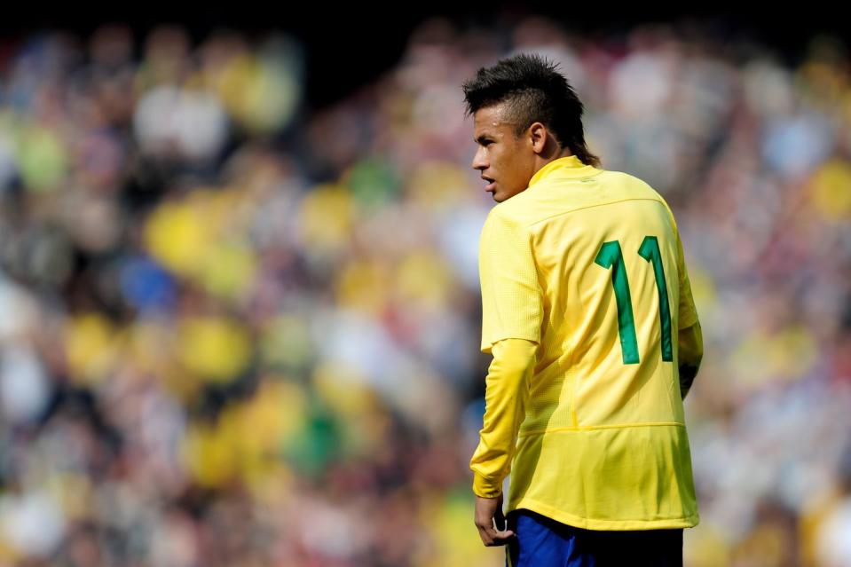 neymar faces away from the camera and looks over his left shoulder, he wears a yellow brazil jersey with green number 11