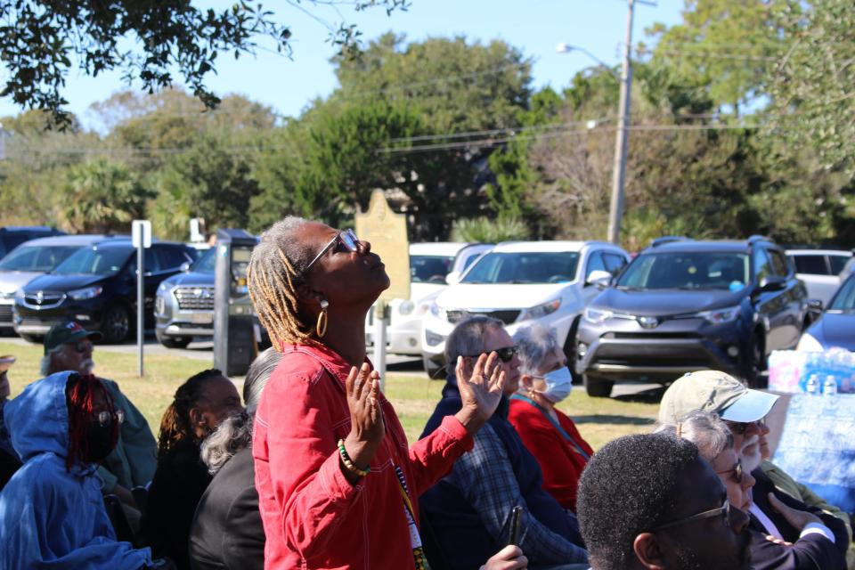 Rosalyn Rouse stands up as Darlene Washington sings a song of healing during Tybee Island's Remembrance Ceremony.