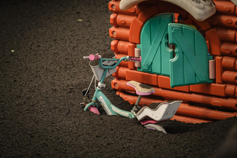 A kid bicycle is buried in volcanic ash as Mount Cumbre Vieja continues to erupt on the Canary island of La Palma in El Paso on September 24, 2021. / Credit: Andres Gutierrez/Anadolu Agency via Getty Images