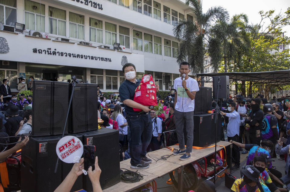 Pro-democracy protest leader Panupong Jadnok, right, speaks as Parit Chiwarak, left, watches from a makeshift stage outside Bang Khen Metropolitan Police Station in Bangkok, Thailand, Monday, Dec. 21, 2020. Several leaders of protest movement report to the police station to answer the charges of defaming the Thai monarchy, the most serious of many offenses of which they stand accused during recent pro-democracy rallies. (AP Photo/Gemunu Amarasinghe)