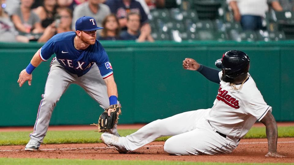 Texas Rangers' Ryan Dorow, left, tags out Cleveland Indians' Franmil Reyes at third base in the eighth inning of a game, Thursday in Cleveland.