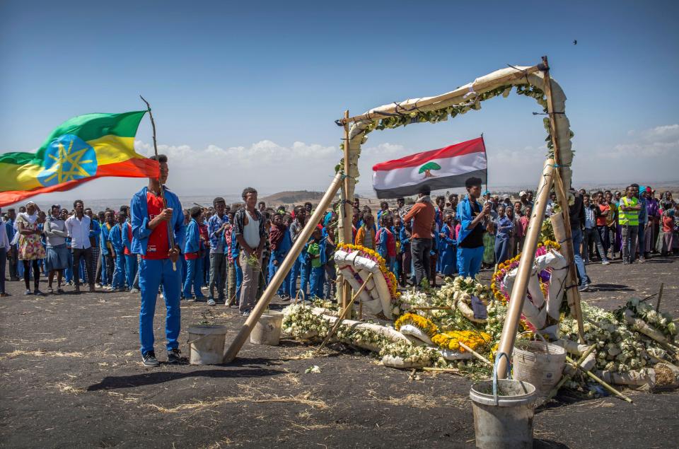 Students from Hama elementary school, who walked an hour and a half from their school in the surrounding area to pay their respects, stand next to floral tributes at the scene where the Ethiopian Airlines Boeing 737 Max 8 crashed shortly after takeoff on Sunday killing all 157 on board, near Bishoftu, south-east of Addis Ababa, in Ethiopia Friday, March 15, 2019. Analysis of the flight recorders has begun in France, the airline said Friday, while in Ethiopia officials started taking DNA samples from victims' family members to assist in identifying remains. (AP Photo/Mulugeta Ayene) ORG XMIT: NAI112