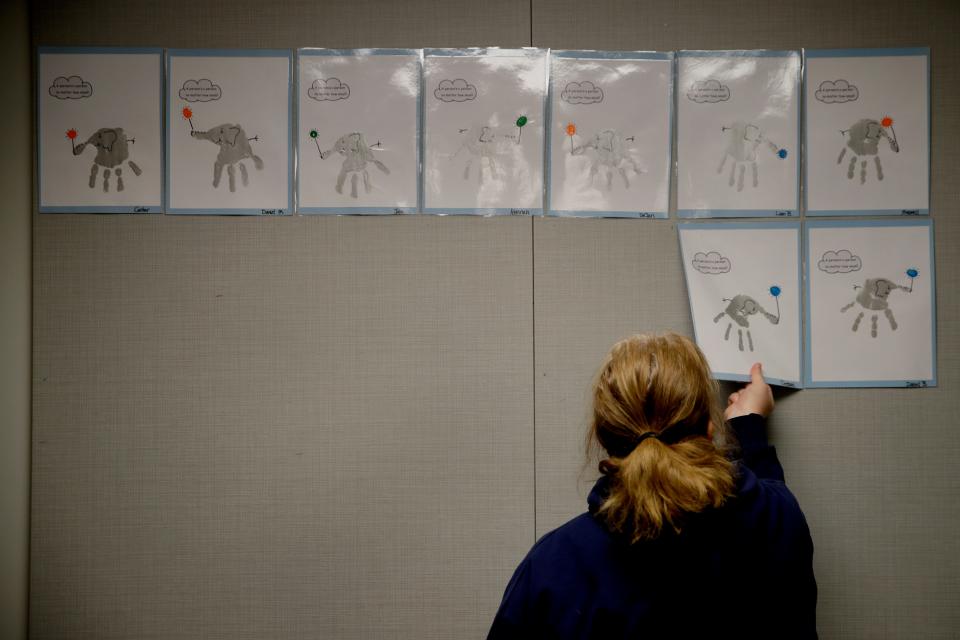 FILE - In this May 12, 2020, file photo, a teacher removes students’ artwork from a bulletin board as she packs the art in her kindergarten classroom at an elementary school in Olathe, Kan. The coronavirus is proving ruinous to state budgets, forcing many governments to consider once-unthinkable cuts to schools, universities, health care programs and a wide array of other basic functions. (AP Photo/Charlie Riedel, File)