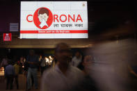 People walk past an electronic billboard displaying Coronavirus disease (COVID-19) safety awareness advertisement at a railway station in Mumbai.