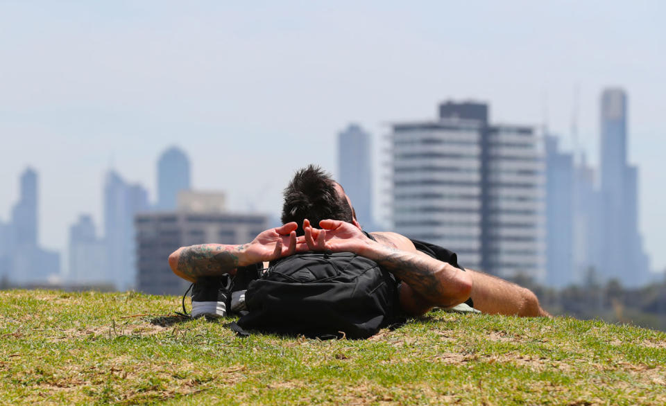 A man is seen sunbathing on the foreshore during a hot day at St Kilda beach in Melbourne. Source: AAP