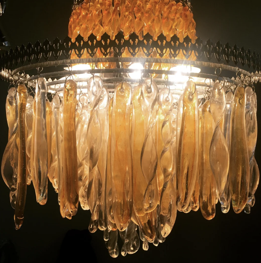 A close-up view of an elegant chandelier, featuring multiple glass teardrop-shaped ornaments hanging from its frame