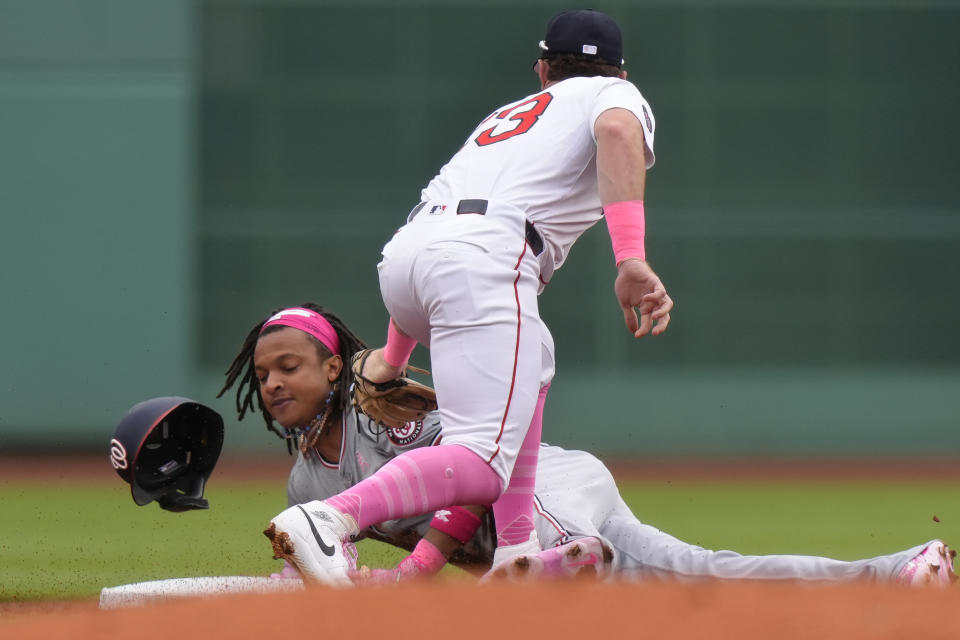Washington Nationals' CJ Abrams, left, is out at second base as he is tagged by Boston Red Sox's Romy Gonzalez, top, in the first inning of a baseball game, Sunday, May 12, 2024, in Boston. (AP Photo/Steven Senne)