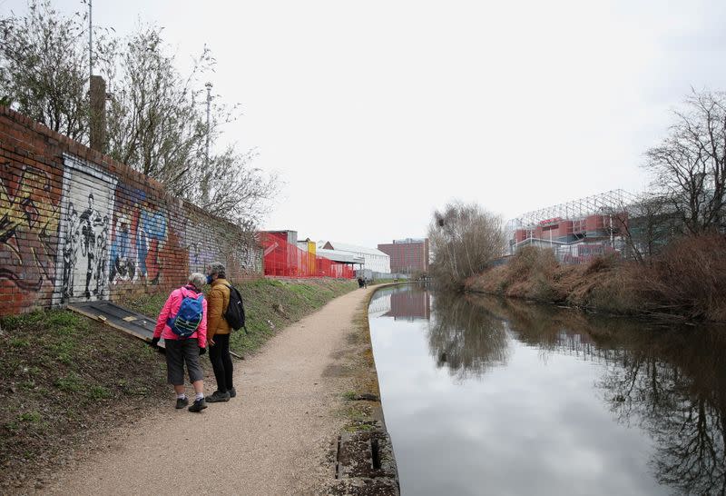 People look at a mural of England soccer player Marcus Rashford kicking down the door of number 10 Downing Street next to Manchester Canal in Manchester