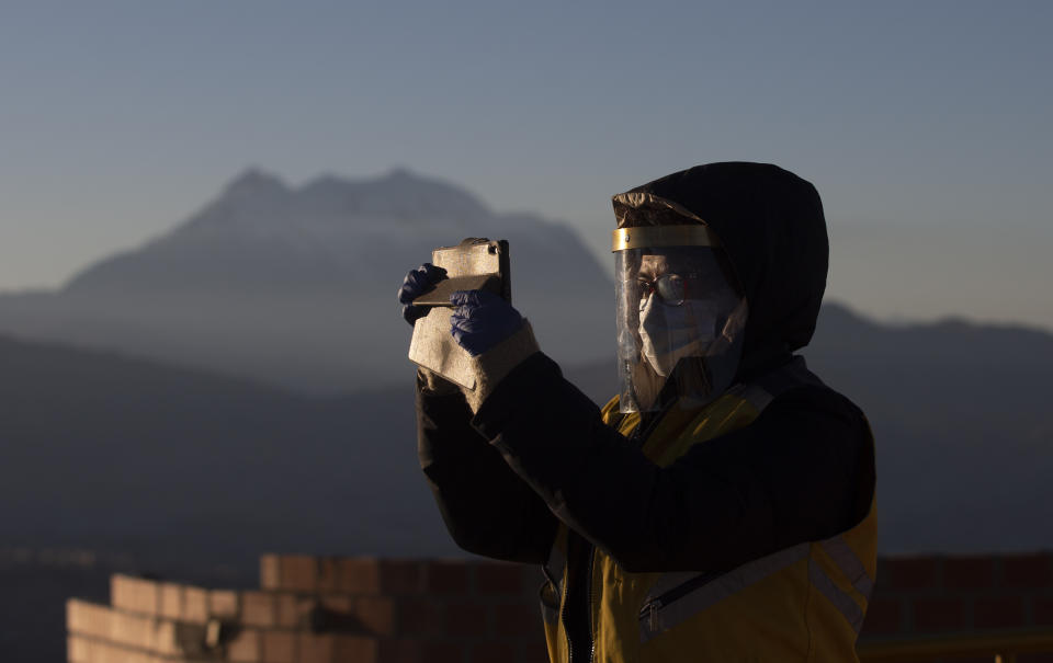 A city employee wearing a face mask amid the spread of the new coronavirus takes a selfie with the first rays of sunlight during a new year's ritual at the Mirador Jach'a Apacheta de Munaypata, in La Paz, Bolivia, early Sunday, June 21, 2020. Aymara indigenous communities are celebrating the Andean new year 5,528. (AP Photo/Juan Karita)