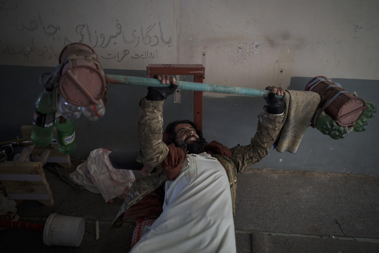 A Taliban fighter lifts a makeshift weight left behind by former prisoners at an empty area of the Pul-e-Charkhi prison in Kabul, Afghanistan, Monday, Sept. 13, 2021. Pul-e-Charkhi was previously the main government prison for holding captured Taliban and was long notorious for abuses, poor conditions and severe overcrowding with thousands of prisoners. Now after their takeover of the country, the Taliban control it and are getting it back up and running, current holding around 60 people, mainly drug addicts and accused criminals. (AP Photo/Felipe Dana)