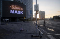 A man rides a bicycle next to a billboard calling people to wear masks, on empty road following new restrictions in the three-week nationwide lockdown, in Tel Aviv, Israel, Saturday, Sept. 26, 2020. (AP Photo/Oded Balilty)