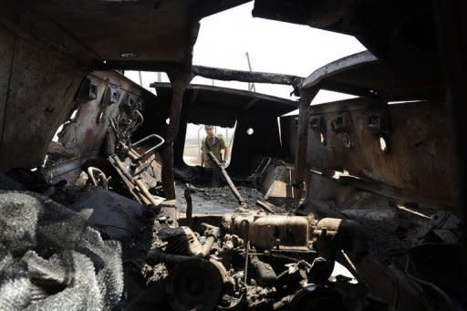 An Israeli soldier inspects a burnt armoured vehicle near the Kerem Shalom border crossing after unidentified gunmen crossed into Israel from Egypt. Egypt's army vowed Monday to "avenge" the killing of 16 troops by the gunmen and President Mohamed Morsi won US backing as he ordered his security forces to take full control of the Sinai