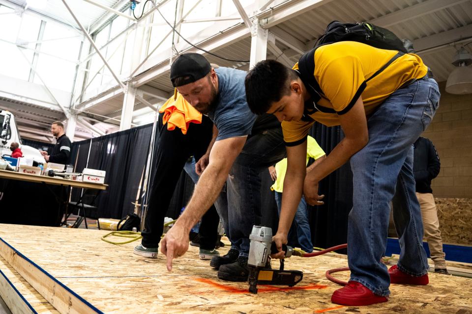Clinton Webster, left, assists a student with a nail gun during Build My Future Iowa at the Iowa State Fairgrounds on Wednesday n Des Moines.