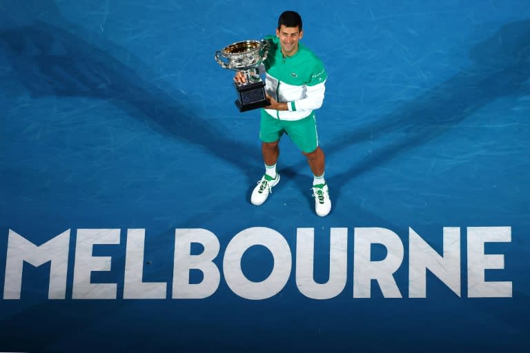 Le Serbe Novak Djokovic avec son trophée après avoir remporté l'Open d'Australie 2021, le 21 février 2021 à Melbourne (AFP/Patrick HAMILTON)