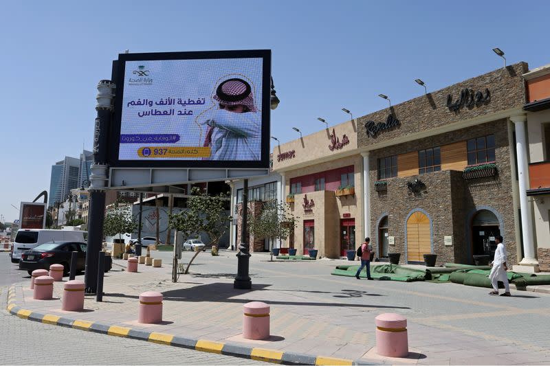 FILE PHOTO: People walk near a banner with an instruction on personnel hygiene, following the outbreak of coronavirus, at a street in Riyadh