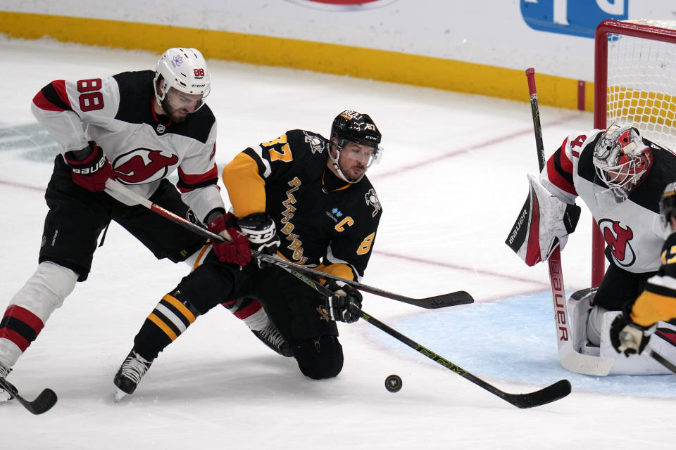 New Jersey Devils' Kevin Bahl (88) hooks Pittsburgh Penguins' Sidney Crosby (87) in front of Devils goalie Vitek Vanecek during the first period of an NHL hockey game in Pittsburgh, Thursday, Nov. 16, 2023. Bail served a two-minute minor penalty for the infraction. (AP Photo/Gene J. Puskar)