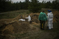 Members of a forensic team work in an exhumation at a mass grave in Lyman, Ukraine, Tuesday, Oct. 11, 2022. (AP Photo/Francisco Seco)