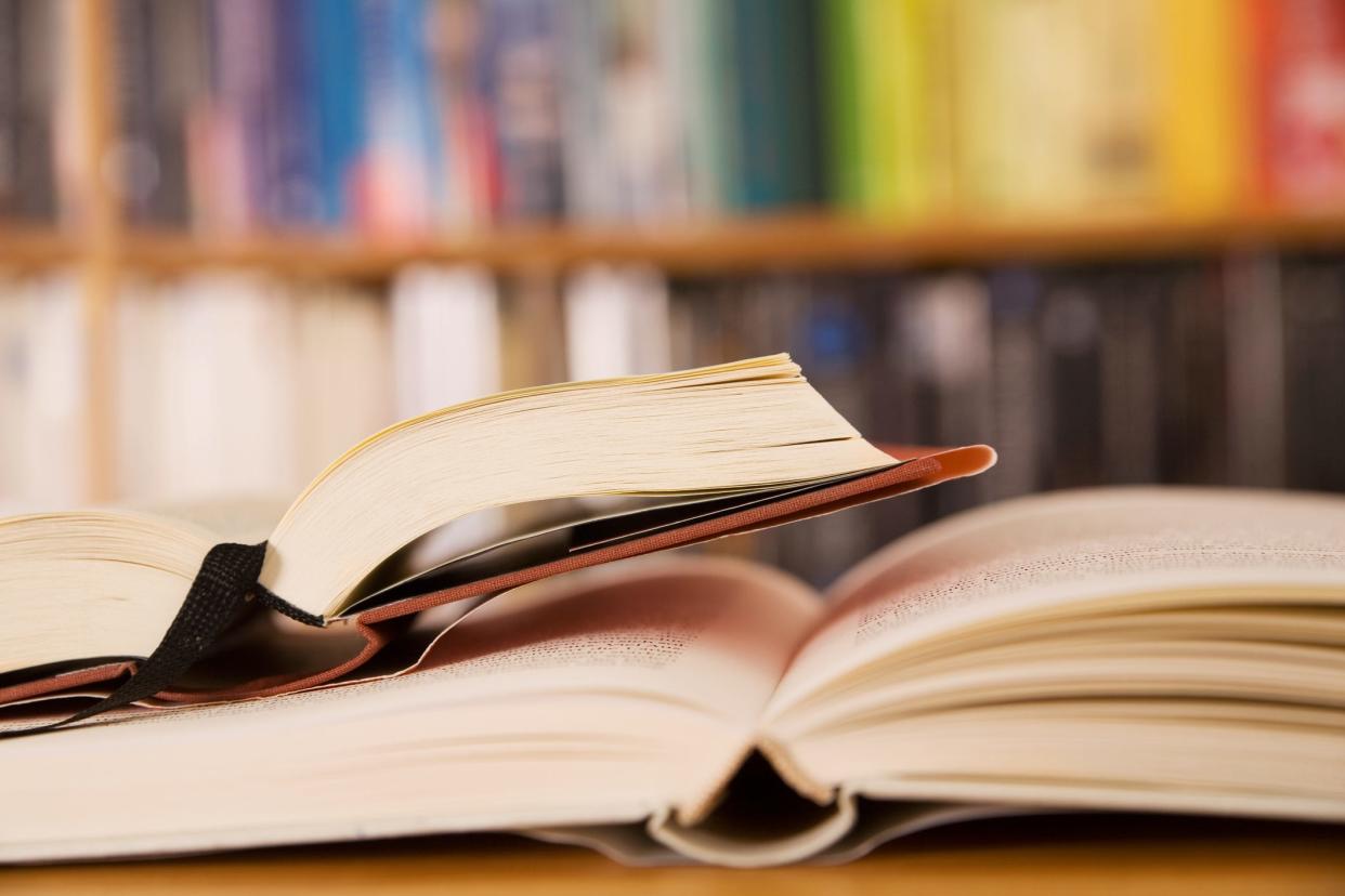 A stock photo shows open books in a library.