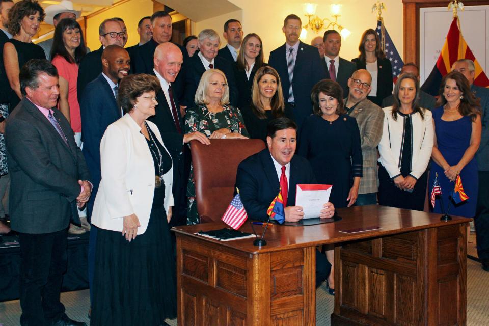 Arizona Gov. Doug Ducey signs legislation to help guide a $1 billion investment in water augmentation and conservation as lawmakers and others look on in Phoenix on July 6, 2022.