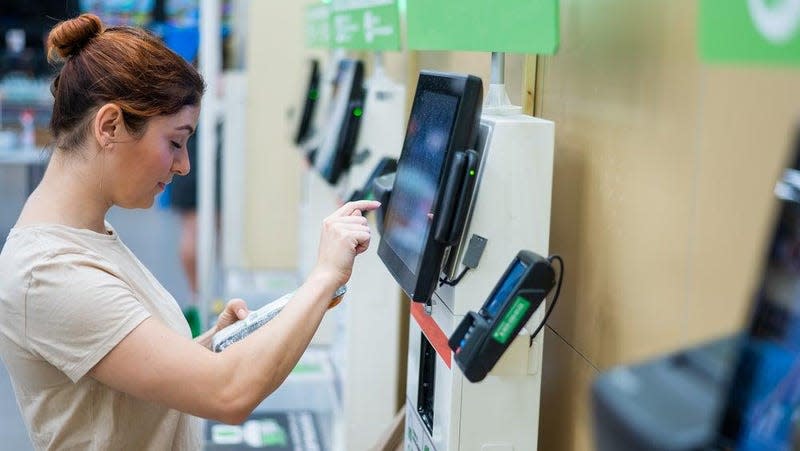 A woman uses a self-checkout kiosk