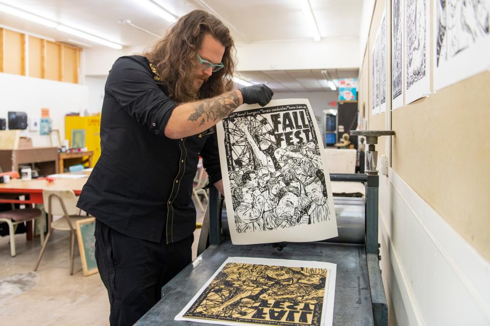 Local artist, author and educator Kyle Darnell pulls a linocut print featured in his new book “Evansville Monsters II: The Book of Dark Days and Other Weird Tales” at the Univeristy of Evansville printmaking studio Tuesday, Nov. 21, 2023.