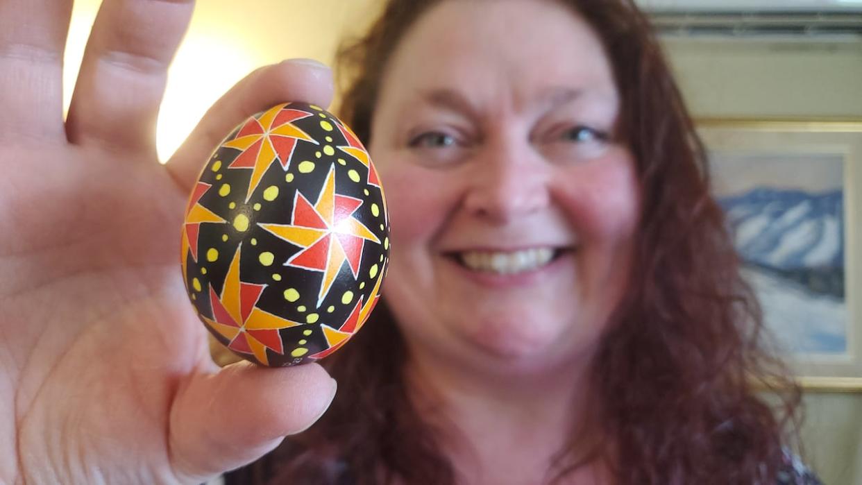 Larissa Reinders, holding a pysanka she made, has been a henna artist for 20 years. She started getting into 'writing pysanky' a little over a year ago. (Shane Fowler/CBC - image credit)