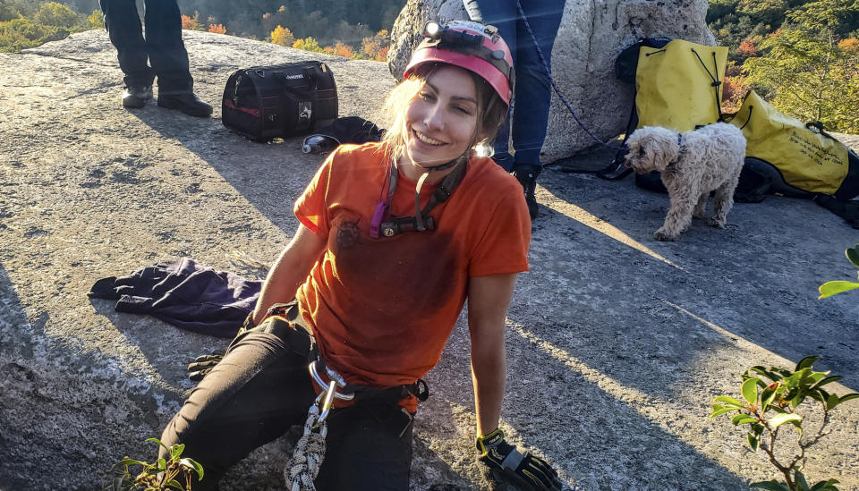 This photo provided by New York State Parks on Wednesday, Oct. 13, 2021, shows park official Jessica Van Ord leaving a fissure after she rescued a 12-year-old dog named Liza, right, found trapped after five days deep inside the narrow, rocky crevice at Minnewaska State Park Preserve in Kerhonkson, N.Y. (New York State Parks via AP)