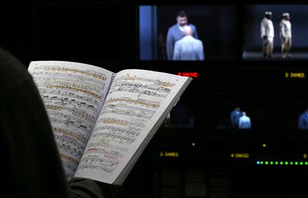 Director Jonathan Haswell looks at the musical score and watches a video feed in the media suite during a live transmission of the opera "Parsifal" from the Royal Opera House in London December 18, 2013. REUTERS/Suzanne Plunkett