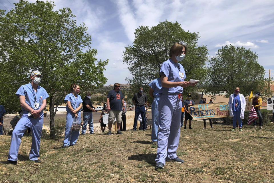 In this photo taken May 8, 2020, medical staff from Rehoboth McKinley Christian Hospital including Chief Medical Officer Val Wangler, center, hold a protest over working conditions and depleted staff in Gallup, N.M. Many nurses and doctors say staffing at the hospital was inadequate because of hospital CEO David Conejo's move to cut back on nurses in the first week of March to offset declining hospital revenues after elective surgeries were suspended. They voiced their discontent at the recent protest calling for his resignation. (AP Photo/Morgan Lee)