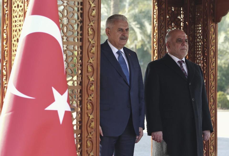 Iraq's Prime Minister Haider al-Abadi, right, and Turkish Prime Minister Binali Yildirim listen to the national anthems during a welcome ceremony in Baghdad, Iraq, Saturday, Jan. 7, 2017. Yildirim is in Iraq for a two-day visit. (Hakan Goktepe, Prime Minister's Press Service, Pool photo via AP)