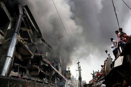 People look at a fire at a packaging factory outside Dhaka, Bangladesh, September 10, 2016. To match Insight BANGLADESH-FIRE/ REUTERS/Mohammad Ponir Hossain/File Photo