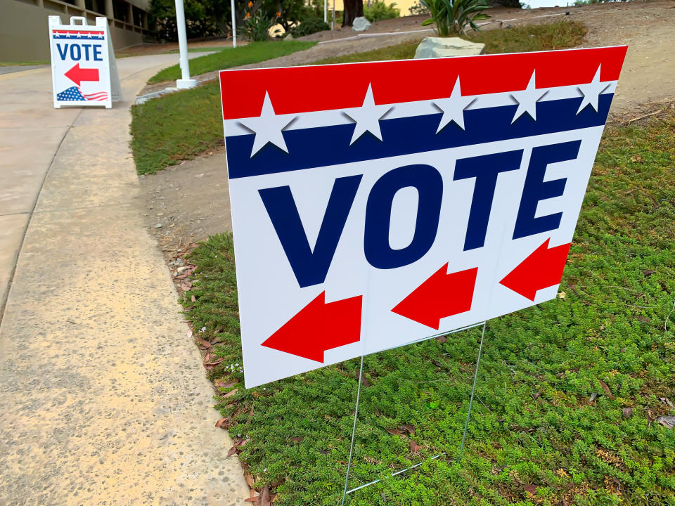 Two "VOTE" signs with arrows pointing towards the direction of a voting location