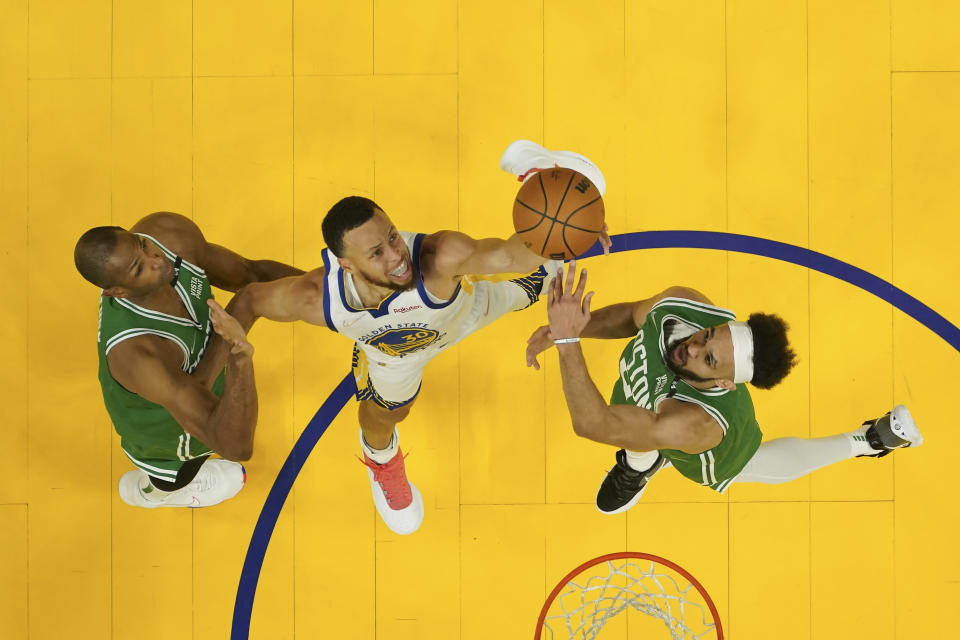Golden State Warriors guard Stephen Curry, middle, looks toward the ball between Boston Celtics center Al Horford, left, and guard Derrick White during the first half of Game 2 of basketball's NBA Finals in San Francisco, Sunday, June 5, 2022. (Ezra Shaw/Pool Photo via AP)