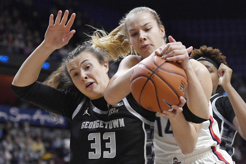 Connecticut's Dorka Juhász, right, grabs a rebound over Georgetown's Graceann Bennett during the first half of an NCAA college basketball game in the quarterfinals of the Big East Conference tournament at Mohegan Sun Arena, Saturday, March 5, 2022, in Uncasville, Conn. (AP Photo/Jessica Hill)