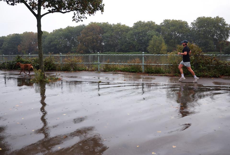 A man runs beside a flooded road by the River Thames (REUTERS)