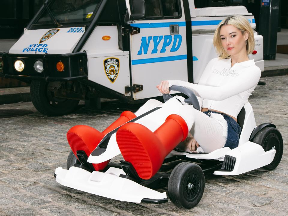 Sarah Snyder in front of NYPD car in MSCHF boots