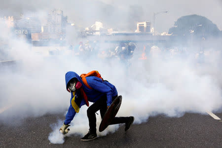 A demonstrator throws back a tear gas grenade at the riot police while rallying against Venezuela's President Nicolas Maduro in Caracas, Venezuela April 24, 2017. REUTERS/Carlos Garcia Rawlins