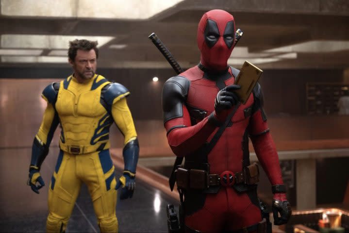 Deadpool holds something as he stands in front of Wolverine.