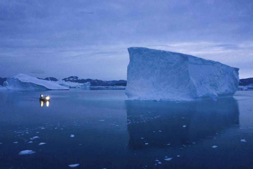 In this Aug. 15, 2019, photo, a boat navigates at night next to large icebergs in eastern Greenland. Greenland's ice has been melting for more than 20 years. (AP Photo/Felipe Dana)