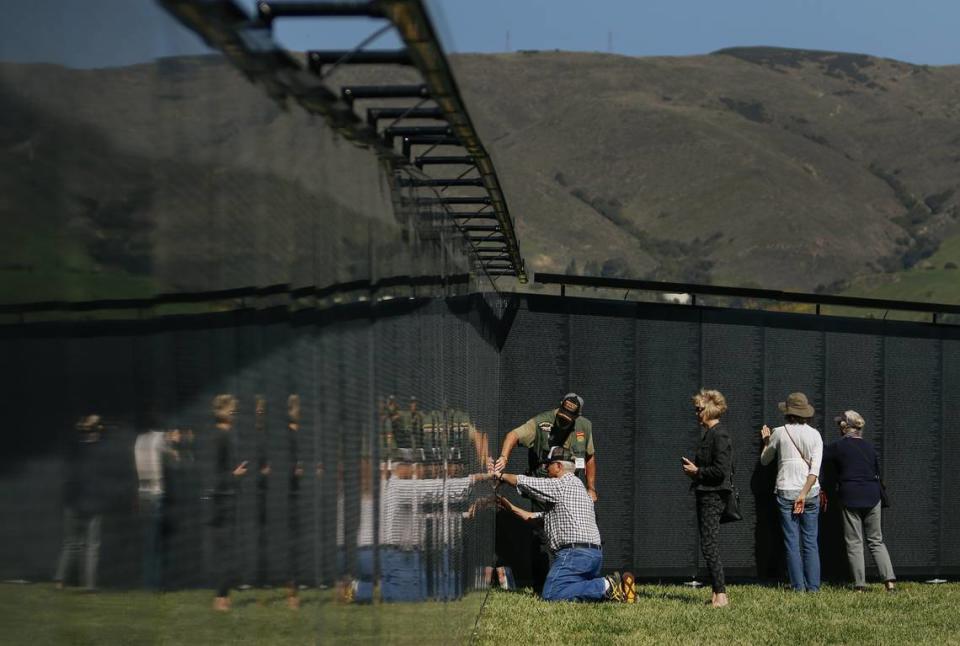 Visitors look for names on “The Wall That Heals,” a three-quarter-scale replica of the Vietnam Veterans Memorial Wall in Washington, D.C., on display at the Madonna Meadows.