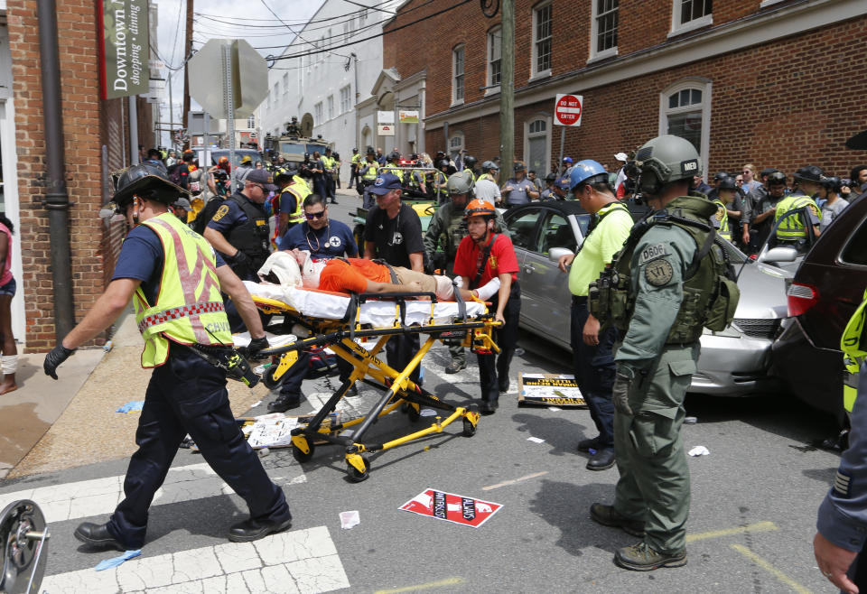 Rescue personnel help injured people after a car ran into a large group of protesters during a white nationalist rally in Charlottesville, Va., Saturday, Aug. 12, 2017. The nationalists were holding the rally to protest plans by the city of Charlottesville to remove a statue of Confederate Gen. Robert E. Lee. There were several hundred protesters marching in a long line when the car drove into a group of them. (AP Photo/Steve Helber)