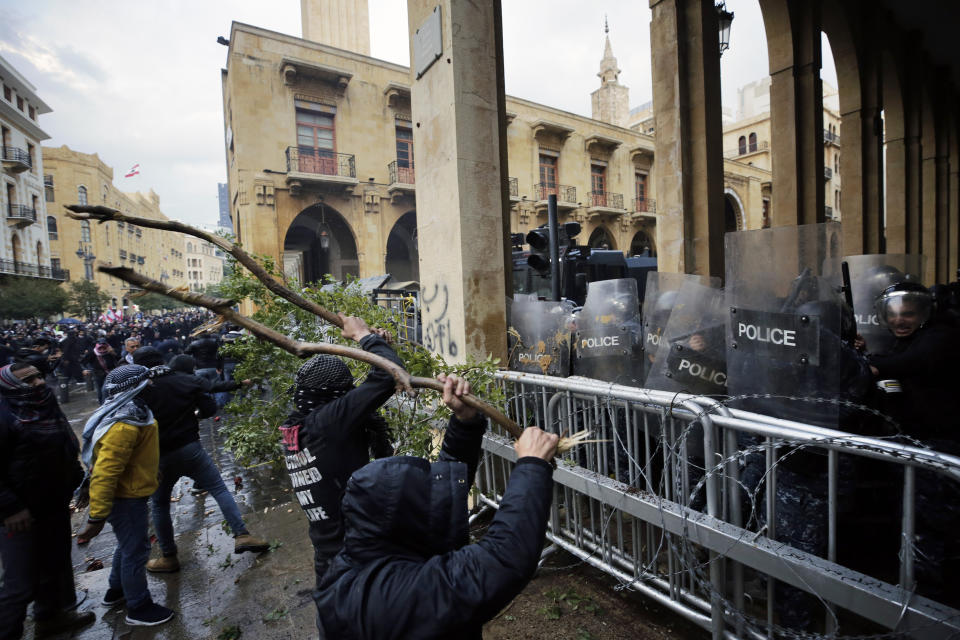 Anti-government demonstrators clash with riot police at a road leading to the parliament building in Beirut, Lebanon, Saturday, Jan. 18, 2020. Riot police fired tears gas and sprayed protesters with water cannons near parliament building to disperse thousands of people after riots broke out during a march against the ruling elite amid a severe economic crisis. (AP Photo/Hassan Ammar)