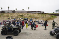U.S. Border Patrol agents direct a group of migrants that have been waiting to apply for asylum between two border walls Friday, May 12, 2023, in San Diego. Hundreds of migrants remain waiting between the two walls, many for days. The U.S. entered a new immigration enforcement era Friday, ending a three-year-old asylum restriction and enacting a set of strict new rules that the Biden administration hopes will stabilize the U.S.-Mexico border and push migrants to apply for protections where they are, skipping the dangerous journey north. (AP Photo/Gregory Bull)