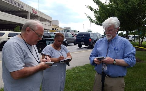 Journalist E.B Furgurson takes notes with two other people as police officers respond to an active shooter inside a city building in Annapolis - Credit: Reuters