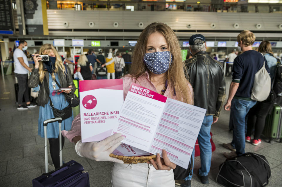 Eine Mitarbeiterin des Tourismusbüros der Balearen zeigt am ersten Reisetag nach Mallorca am Frankfurter Flughafen die Info-Materialien für die Touristen (Bild: Thomas Lohnes/Getty Images)