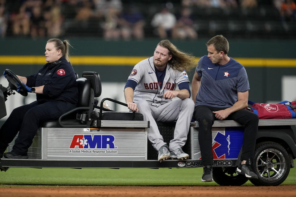 Houston Astros relief pitcher Ryne Stanek is carted off the field attended to by team medical staff, right, and an emergency responder, left, in the ninth inning of a baseball game against the Texas Rangers, Monday, Sept. 4, 2023, in Arlington, Texas. Stanek suffered a lower leg injury covering first on a Rangers' Leody Taveras single. (AP Photo/Tony Gutierrez)