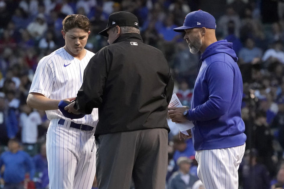 Umpire Hunter Wendelstedt, center, checks the cap and glove of Chicago Cubs relief pitcher Keegan Thompson, left, as manager David Ross watches during the middle of the fifth inning of a baseball game against the Cleveland Indians, Monday, June 21, 2021, in Chicago. (AP Photo/Charles Rex Arbogast)