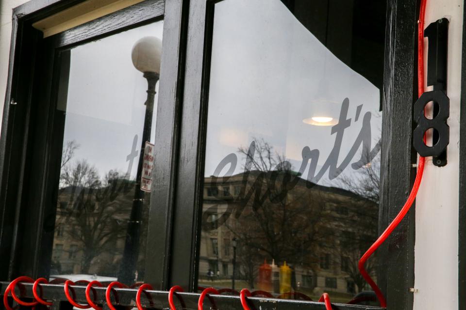 The University of Iowa campus is reflected in Short’s Burgers & Shine's window on Clinton Street Wednesday, Feb. 7, 2024 in Iowa City, Iowa.
